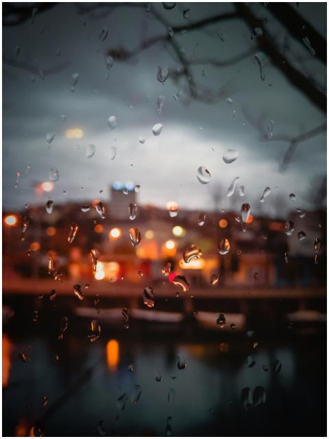 A cityscape at dusk blurred by raindrops on a wind