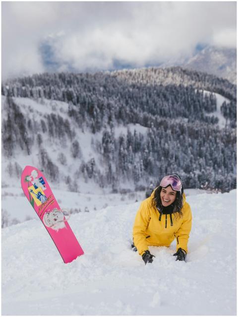 Woman in yellow jacket snowboarding on a snowy mou