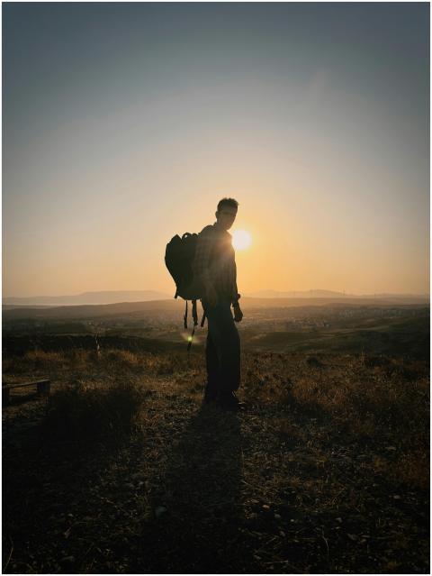 Silhouette of a hiker with backpack in a vast land