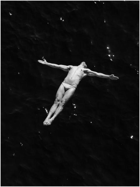 A bold diver mid-flight with arms stretched, over