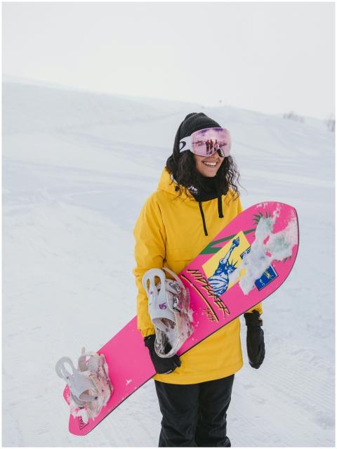 Cheerful woman snowboarder with pink board enjoyin