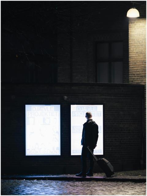 A person stands at night looking at illuminated po