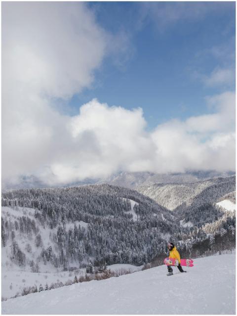 Snowboarder in yellow jacket on a snowy mountain w