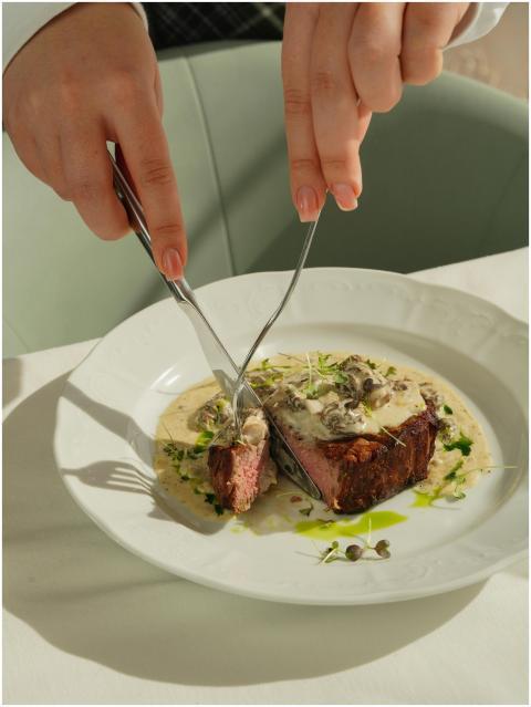 Close-up of a steak being cut, served with creamy