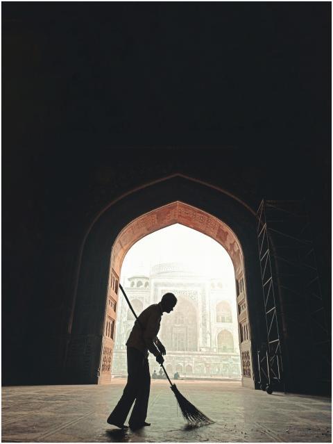 Silhouette of a cleaning person inside an archway