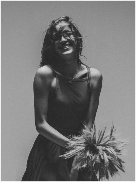 Monochrome portrait of a smiling woman holding a d