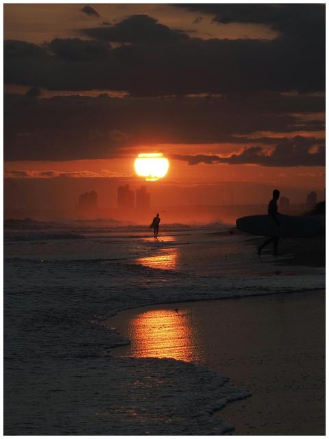 Dramatic silhouetted surfers against a vibrant oce