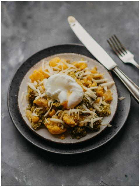 A plate of steamed broccoli and cauliflower topped