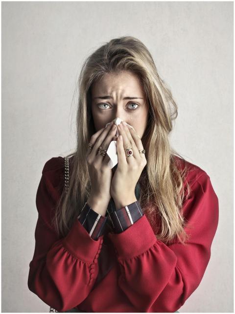 Portrait of a woman sneezing with a tissue, depict