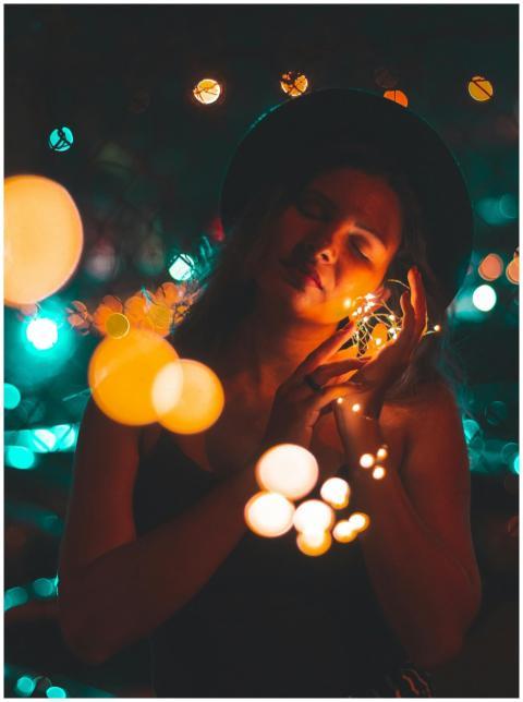 A woman in a hat poses with illuminated string lig