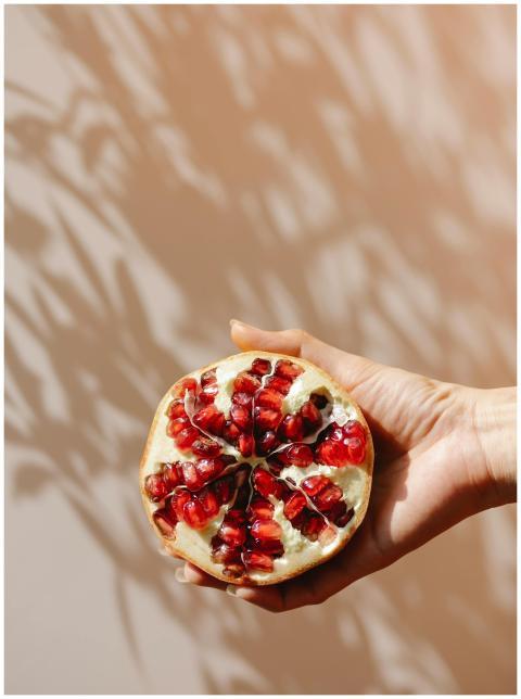 Pomegranate half held against warm shadows, showca