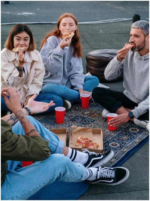 A group of friends enjoying pizza on a rooftop, re