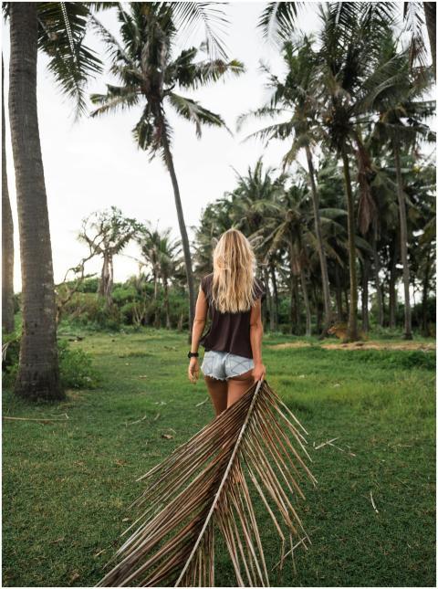 A woman with blonde hair walks in a tropical field
