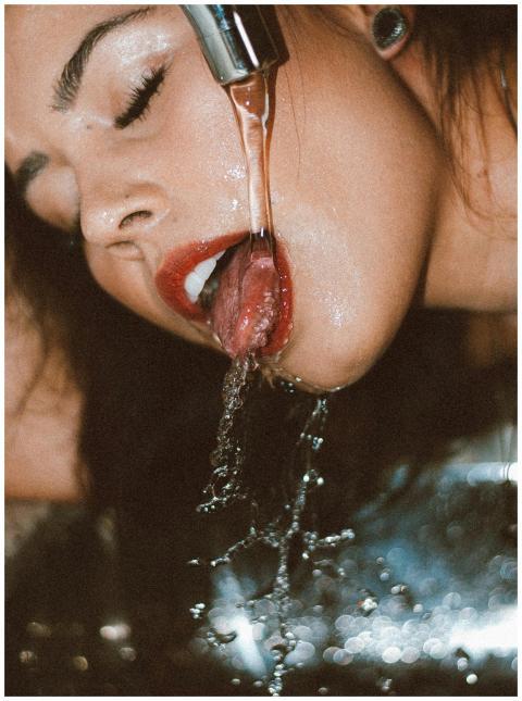 A close-up shot of a woman drinking fresh water fr