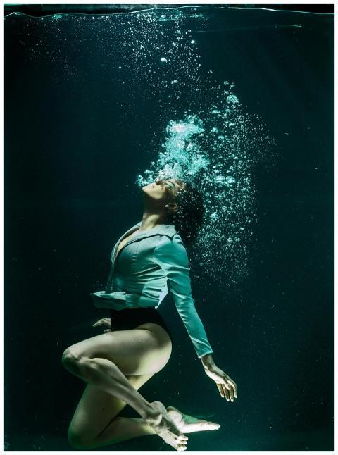 Dramatic photo of a woman diving underwater in sty