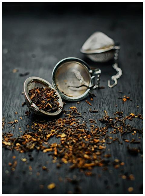 Loose dried tea leaves scattered with a metal tea