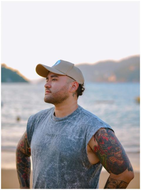 Portrait of a tattooed man in a cap standing confi