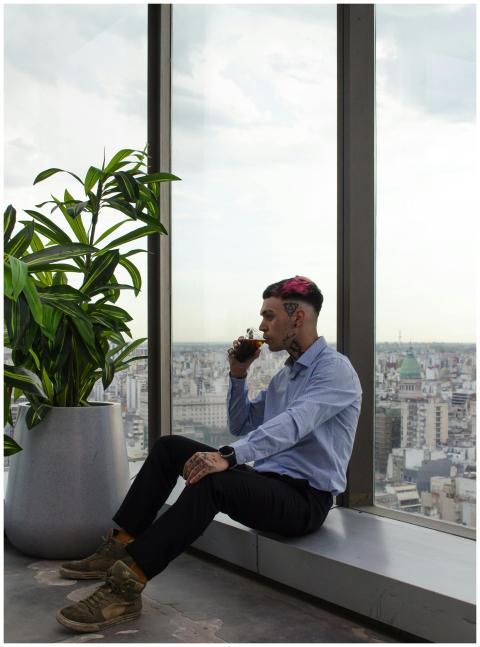 Man sits by window drinking coffee, overlooking ci