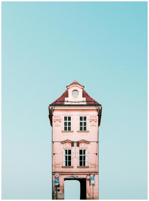 A quaint pink house with red roof against a clear