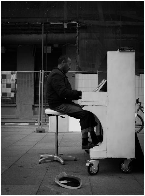 A street musician plays piano on an urban sidewalk