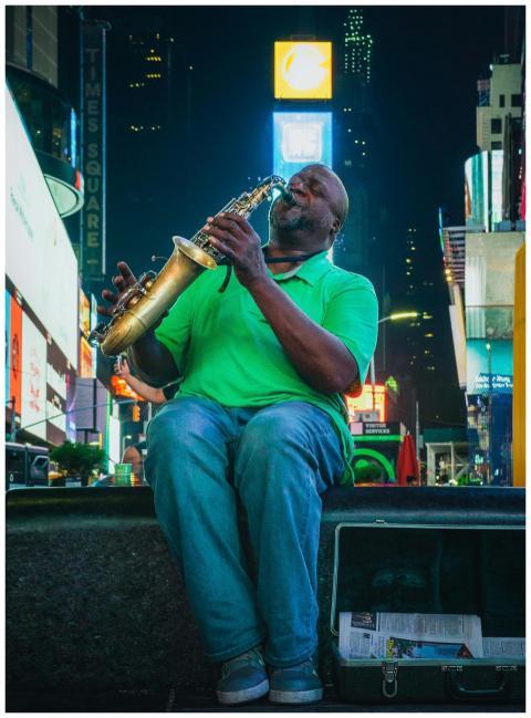Street musician playing saxophone in vibrant Times