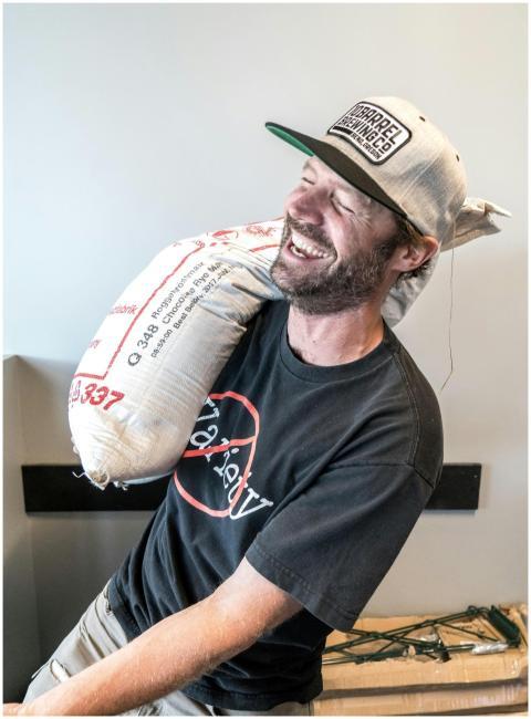 A happy worker in a black shirt and cap carrying a