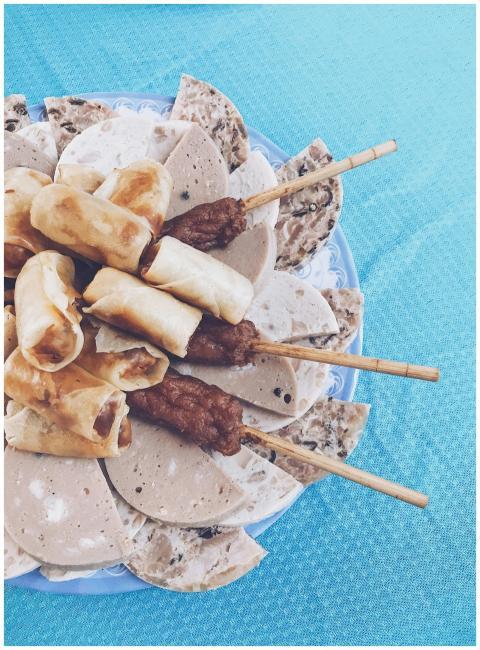 A plate of diverse Asian snacks including meat ske