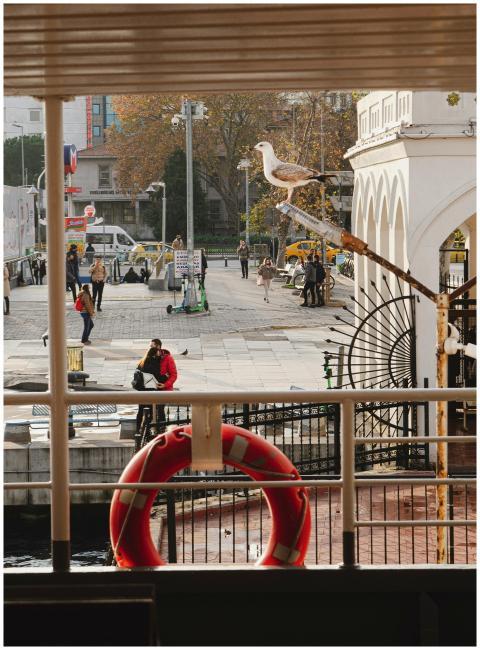 A bustling seaside promenade with a seagull perche