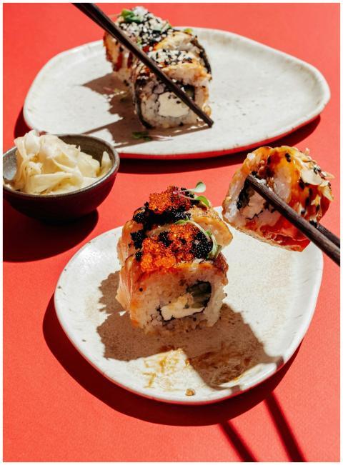 Close-up of tasty sushi rolls on plates with ginge