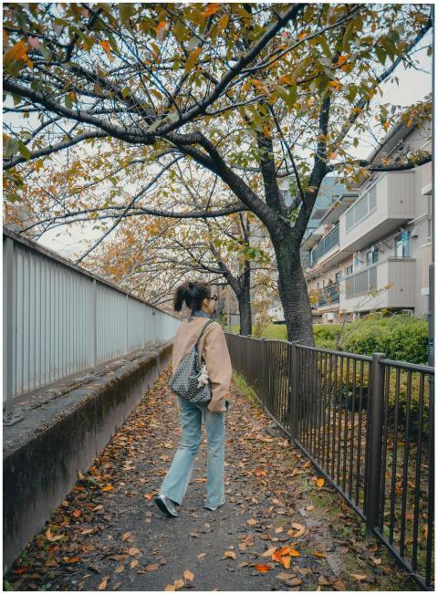 A woman walks along a picturesque path with autumn