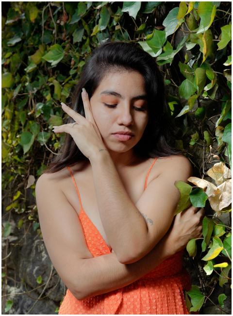 Woman in orange dress posing thoughtfully against