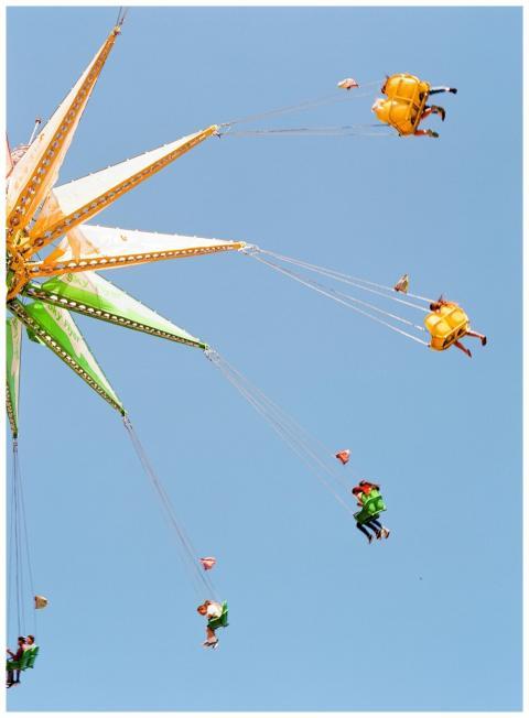 People enjoy a high swing ride against a clear blu