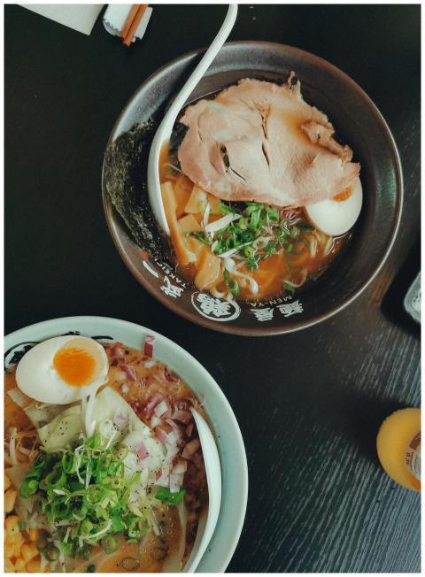 Top view of two ramen bowls with eggs, meat, and g