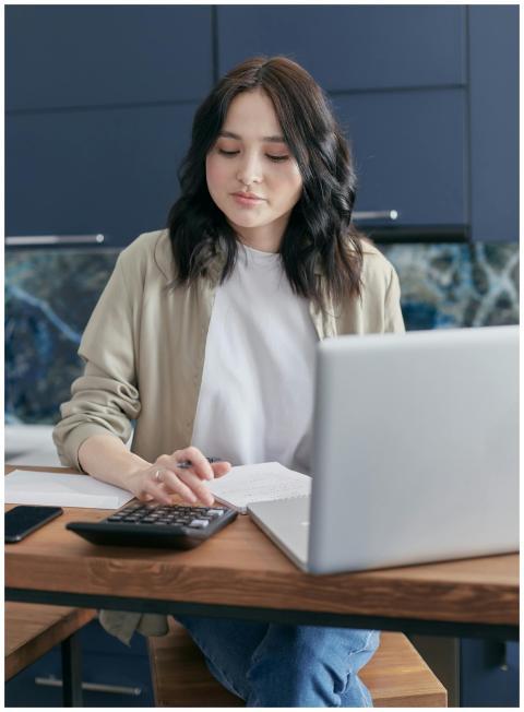 A young woman calculating finances at home using a