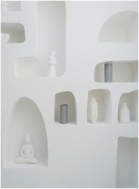 White niches in a wall displaying minimalist figur
