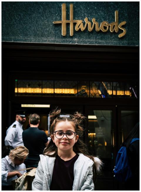 Smiling girl with glasses standing outside Harrods