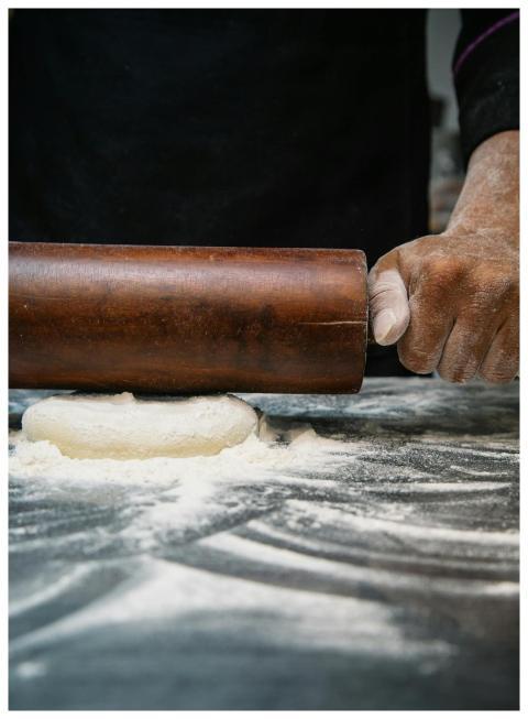 Close-up of a chef rolling dough with a wooden pin