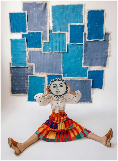 A woman in a colorful outfit hides her face with a