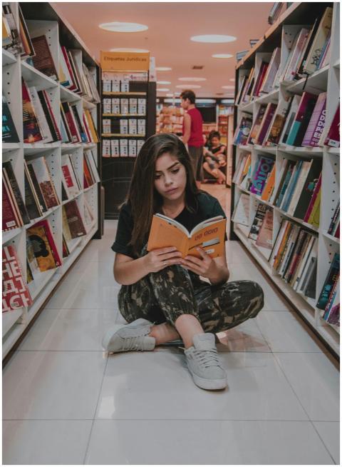 Young woman sitting on the floor and reading a boo