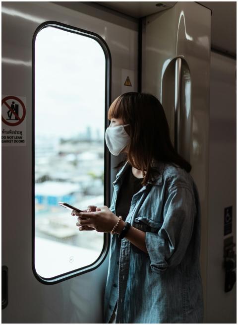 Asian woman wearing face mask, holding smartphone,
