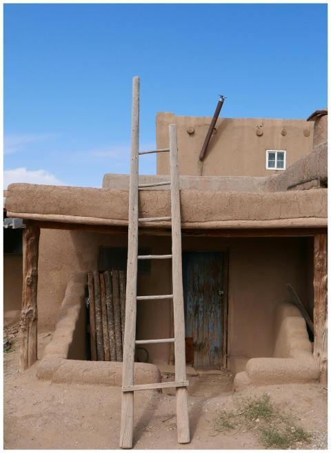 Rustic adobe building with a wooden ladder in Taos