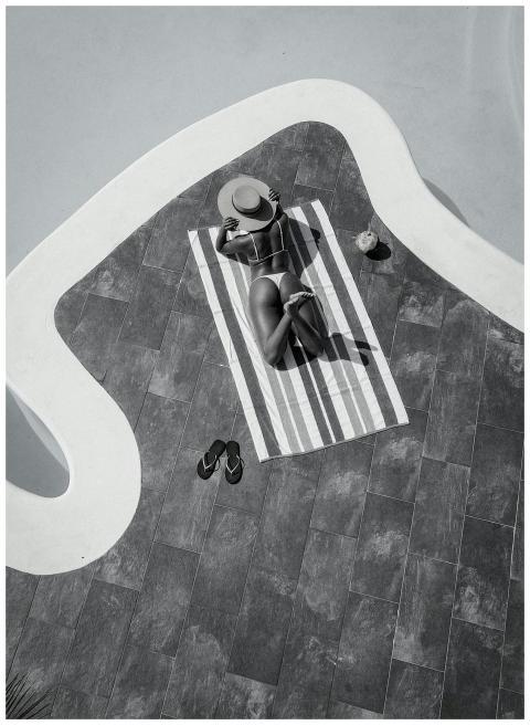 Black and white image of a woman sunbathing on a t