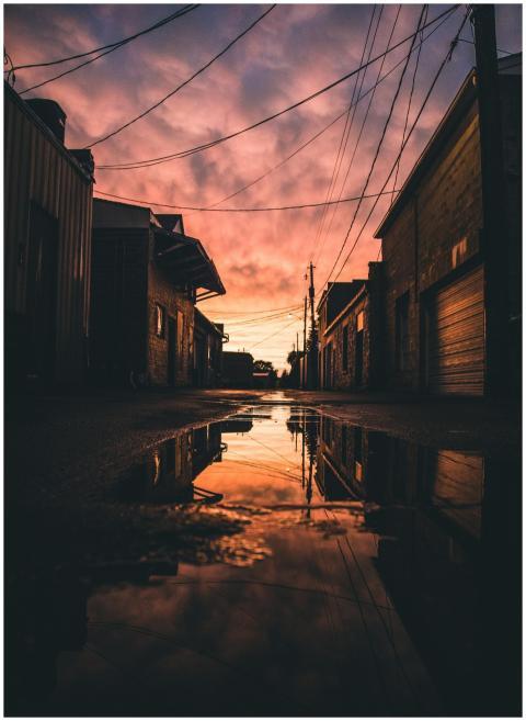 A serene urban alley at sunset with reflections in