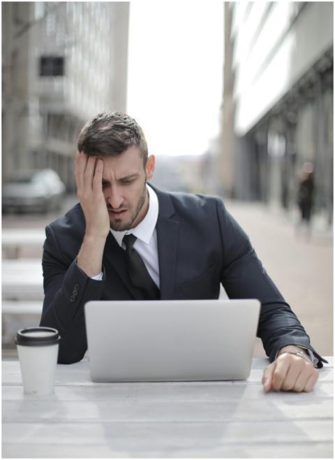 A businessman in a suit looking stressed while usi