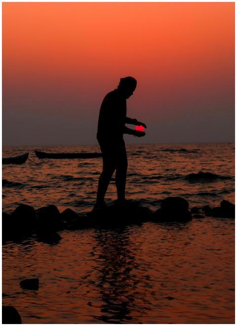 A person silhouetted against an orange sunset stan
