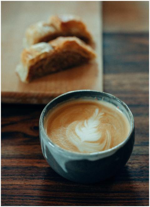Artful cappuccino with latte art beside a pastry i