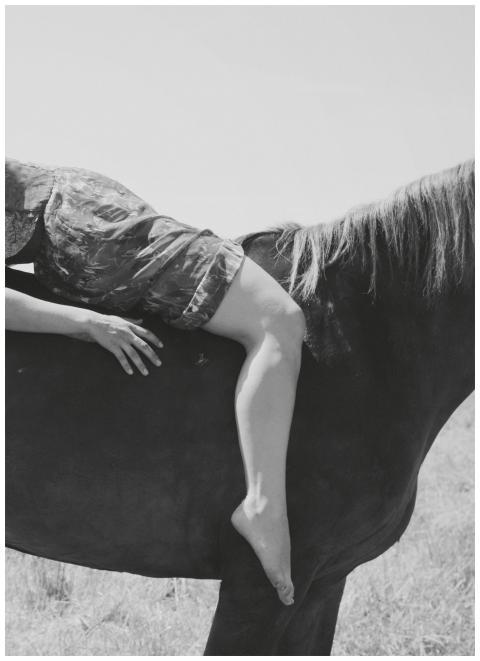 Black and white image of a person lying on a horse