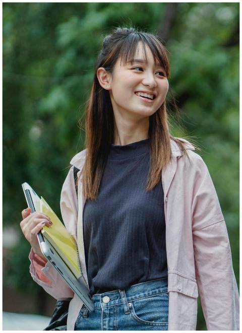 Smiling young Asian woman carrying a laptop and bo