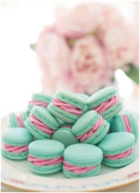 A stack of blue macarons with pink filling on a de