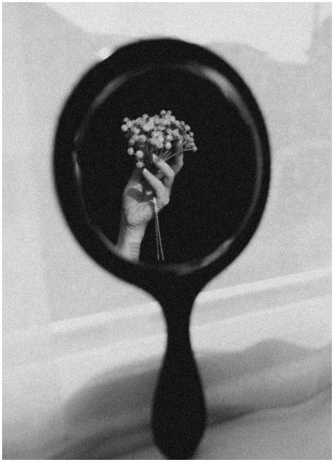 Black and white photo of a hand holding flowers re